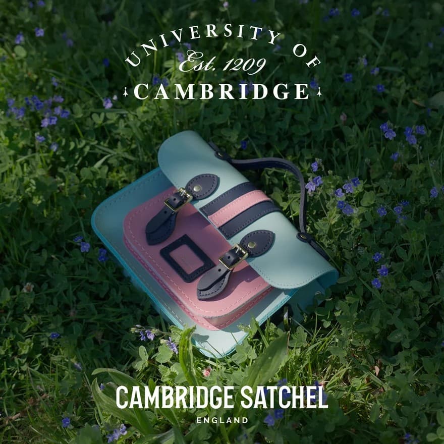 Cambridge Satchel in honeysuckle print resting on grass with wildflowers