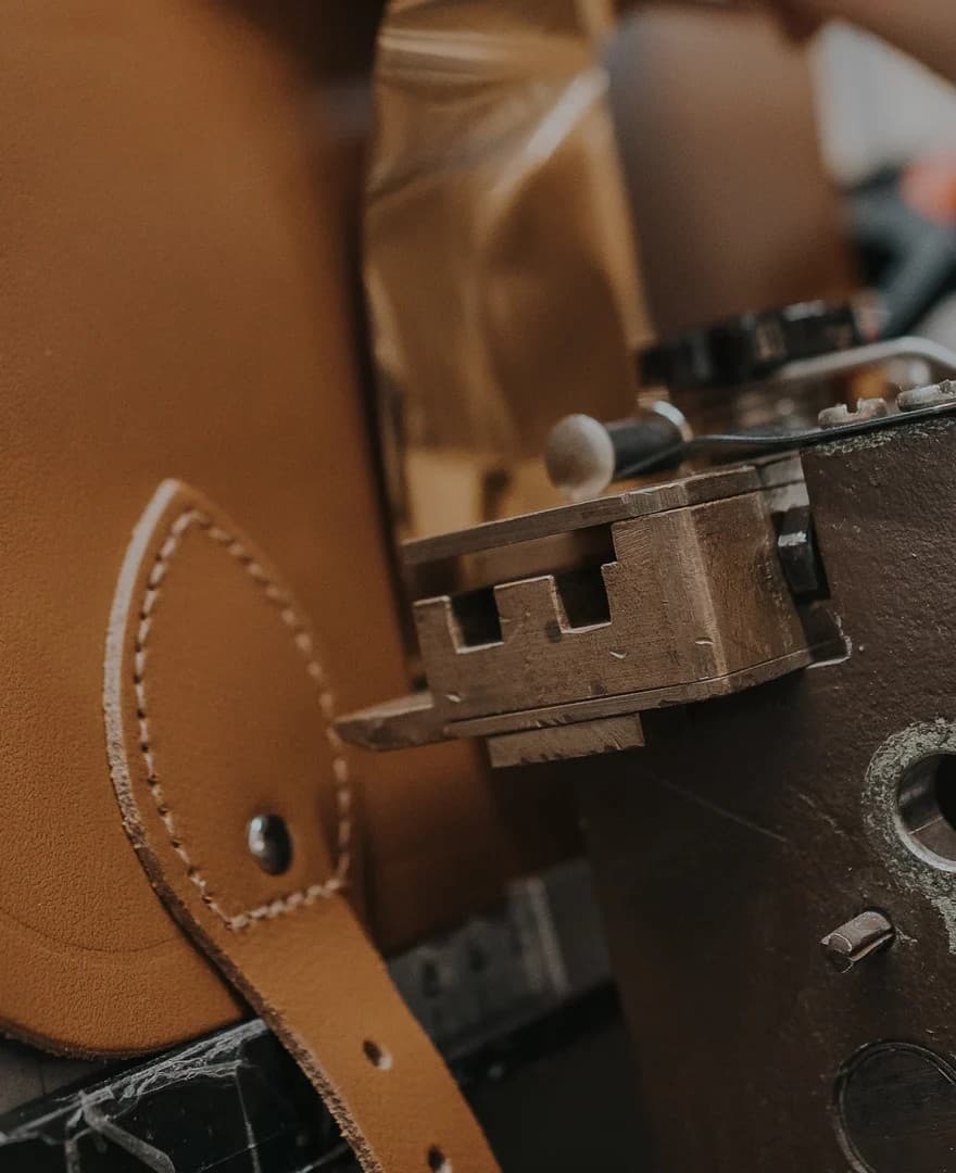 Close-up of leatherworking machinery carefully stitching tan leather in our English workshop