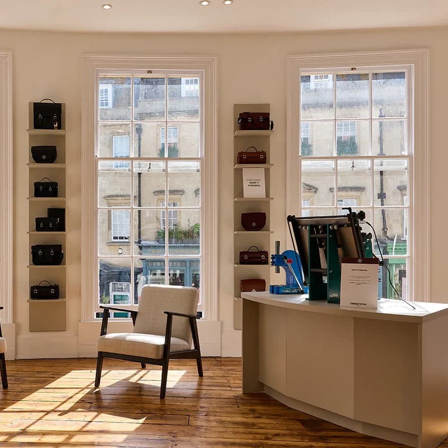 Bright Cambridge Satchel boutique showroom with leather bags displayed on shelves by tall windows